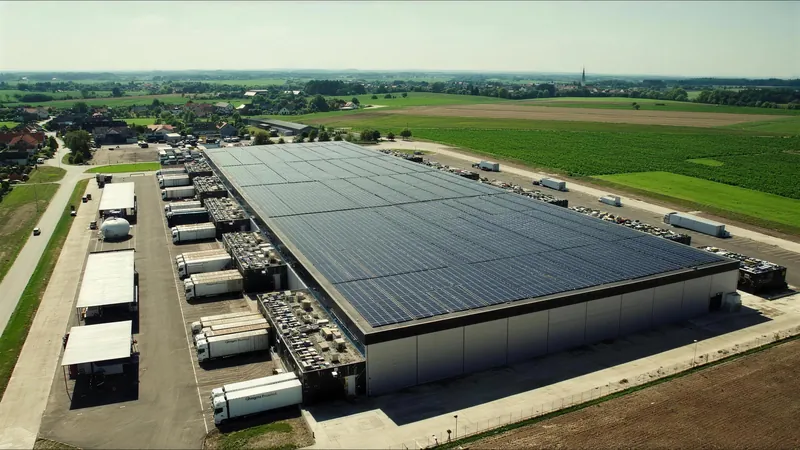 Luftaufnahme eines Logistikzentrums mit Solardach und Lkw an den Verladerampen